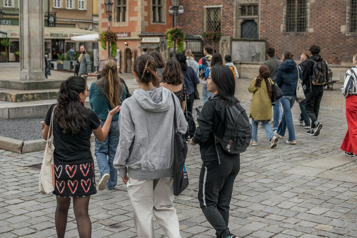 Group of tourists exploring the historic cobblestone streets of Wrocław old town, Poland