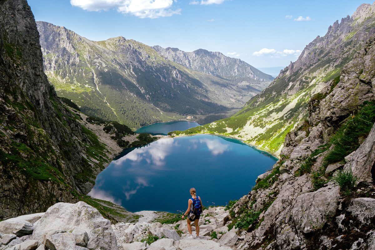 Hiker overlooking the deep blue Morskie Oko lake in the Tatra Mountains near Zakopane, Poland