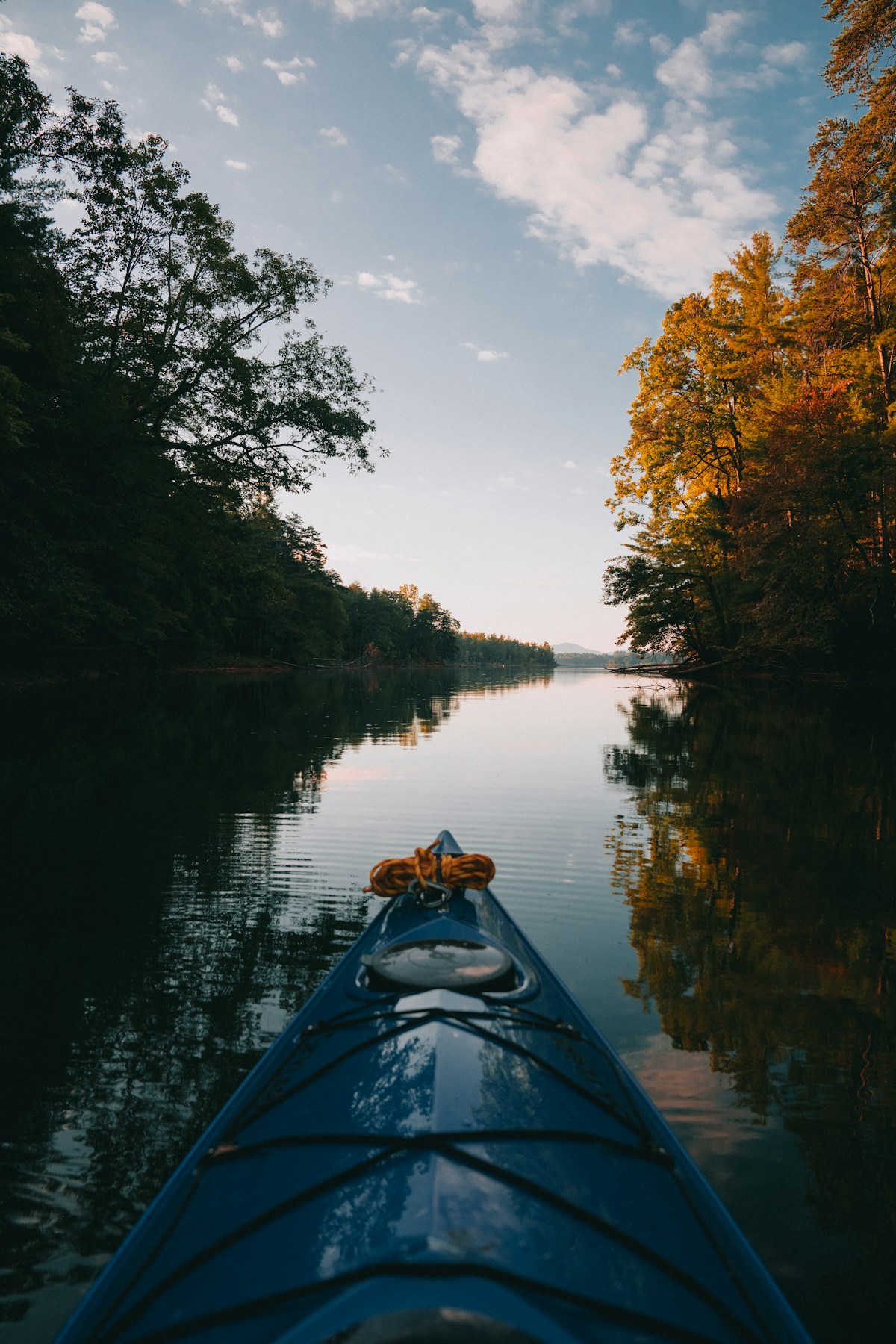 Blue kayak on a calm forested lake at dusk, Masurian Lakeland, Poland