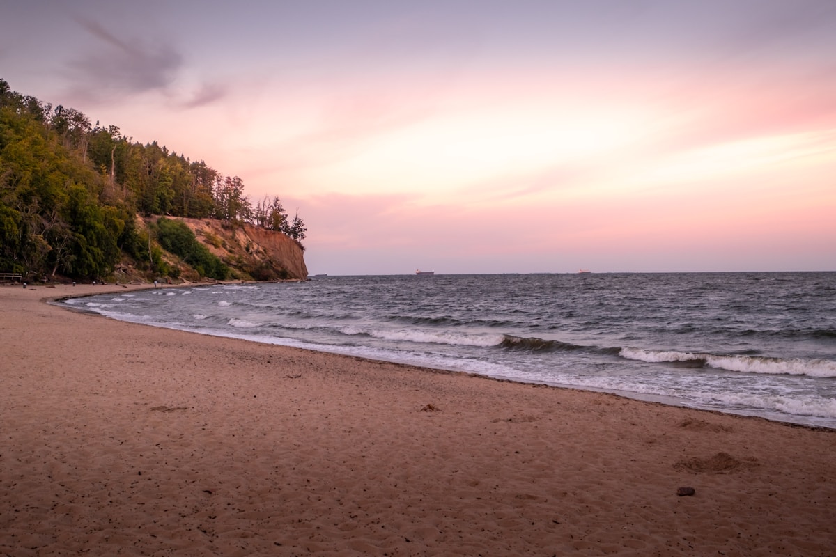 Sandy beach at sunset with a wooded glacial cliff at Orłowo, Gdynia, Poland