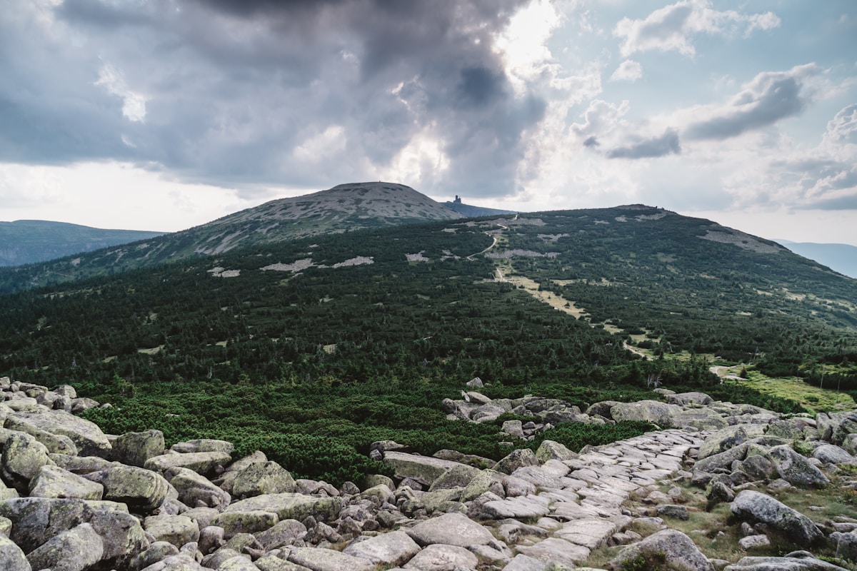 Rocky mountain trail in Karkonosze National Park with summit observation tower visible in the distance, southern Poland