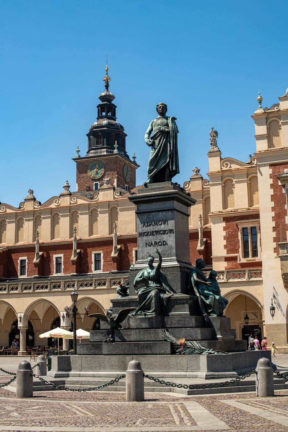 Adam Mickiewicz Monument in front of the Cloth Hall on Kraków's Main Market Square under blue sky, Poland