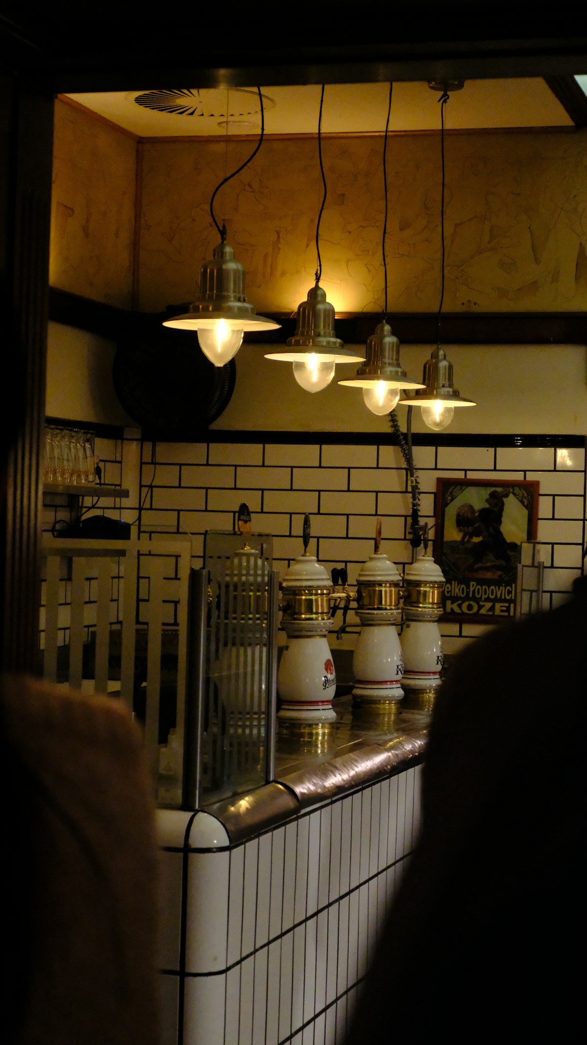 Vintage pendant lights over a bar counter with beer taps in Kraków, Poland