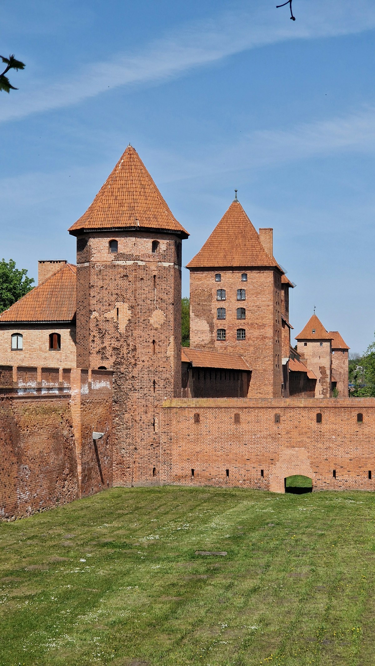 Red-brick Teutonic medieval castle with towers and defensive walls against a blue summer sky in northern Poland