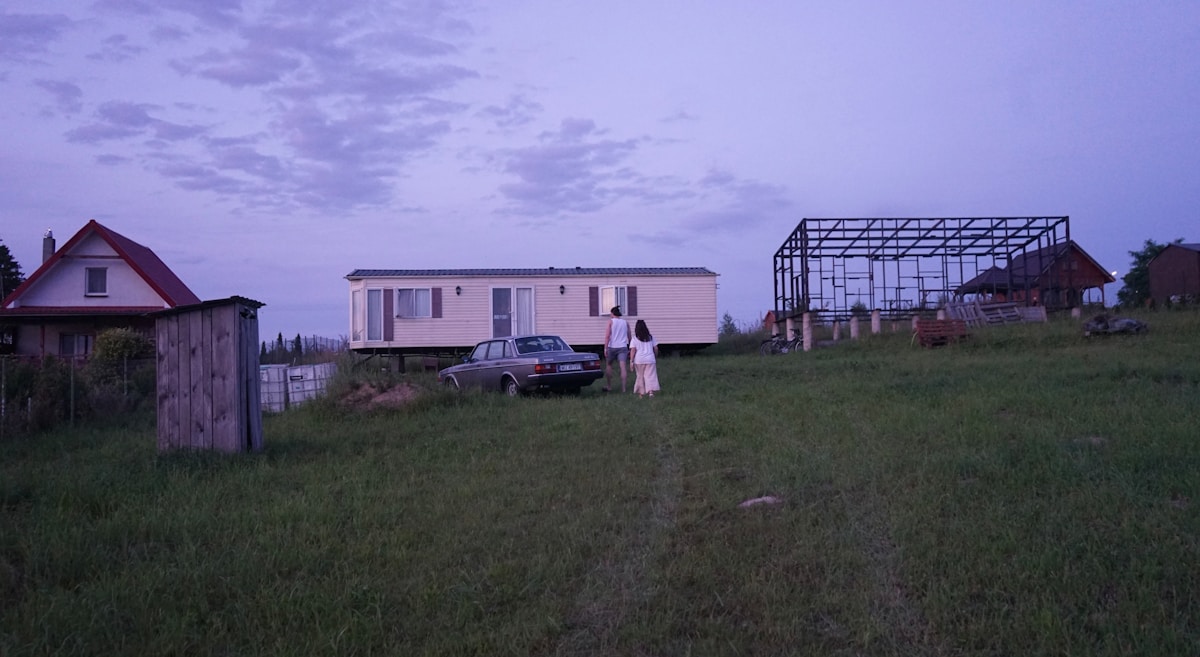 Person standing in a field next to a traditional house in the Warsaw countryside, Poland
