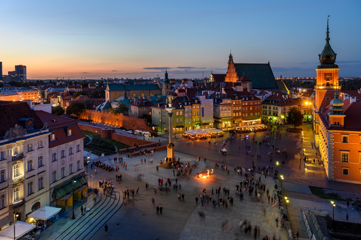 Aerial view of Warsaw Old Town illuminated at dusk with the Royal Castle and Sigismund Column