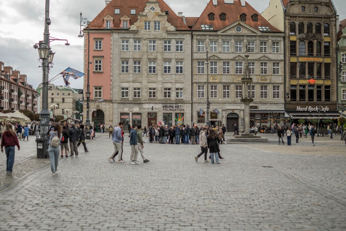 Wrocław Market Square with colourful townhouses and people walking on cobblestones, Poland