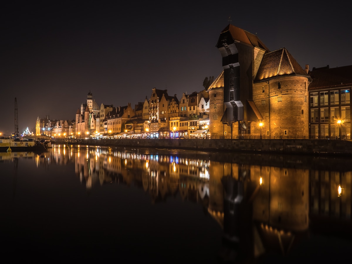 Gdansk waterfront with the medieval Crane and illuminated buildings reflected in the Motlawa River at night, Poland