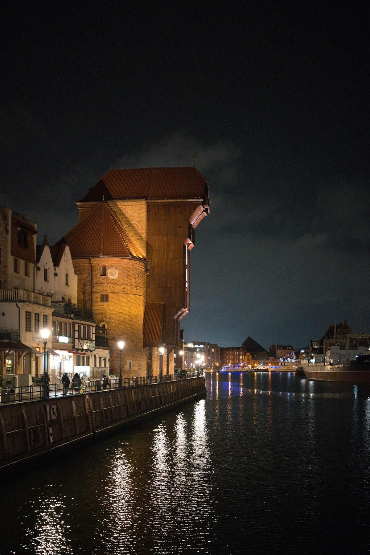 The Crane (Żuraw) and historic waterfront buildings illuminated at night in Gdańsk, Poland