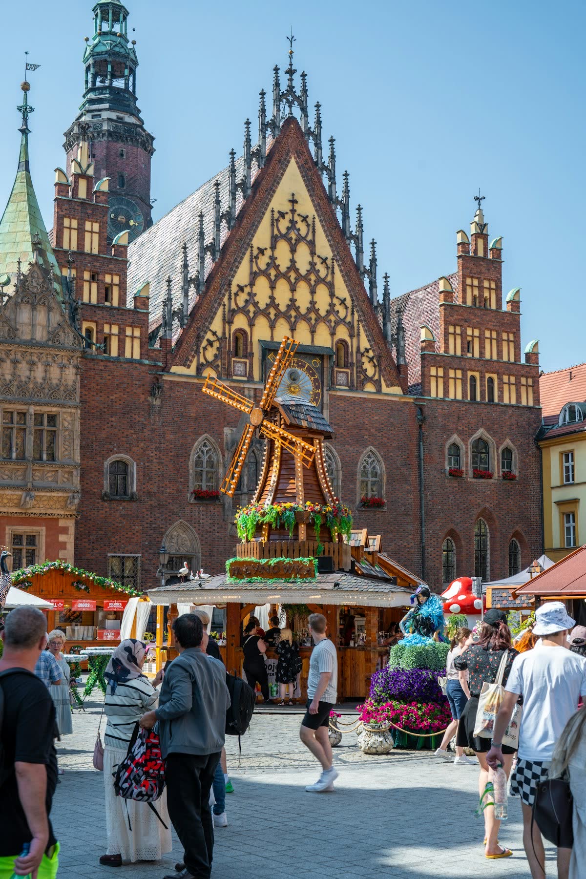 People exploring a summer market near Wrocław Town Hall in Market Square, Poland