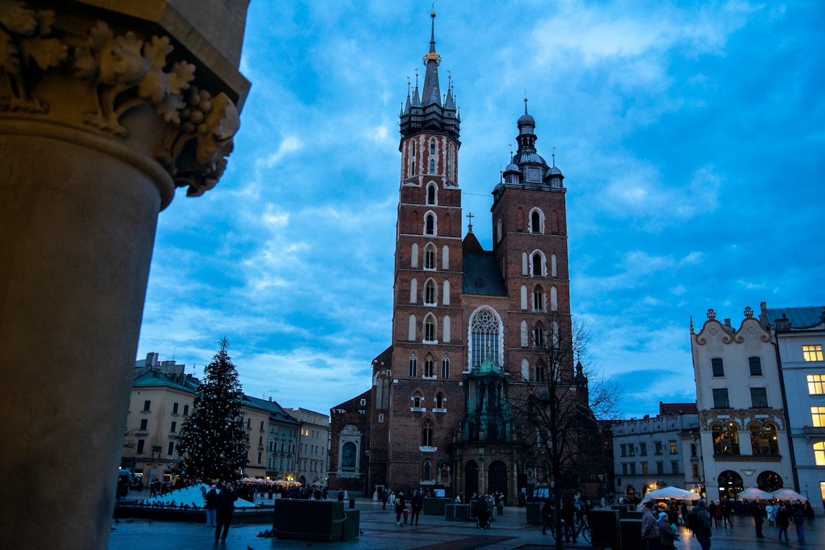 Christmas market stalls on Kraków's Rynek Główny with St Mary's Basilica illuminated at night