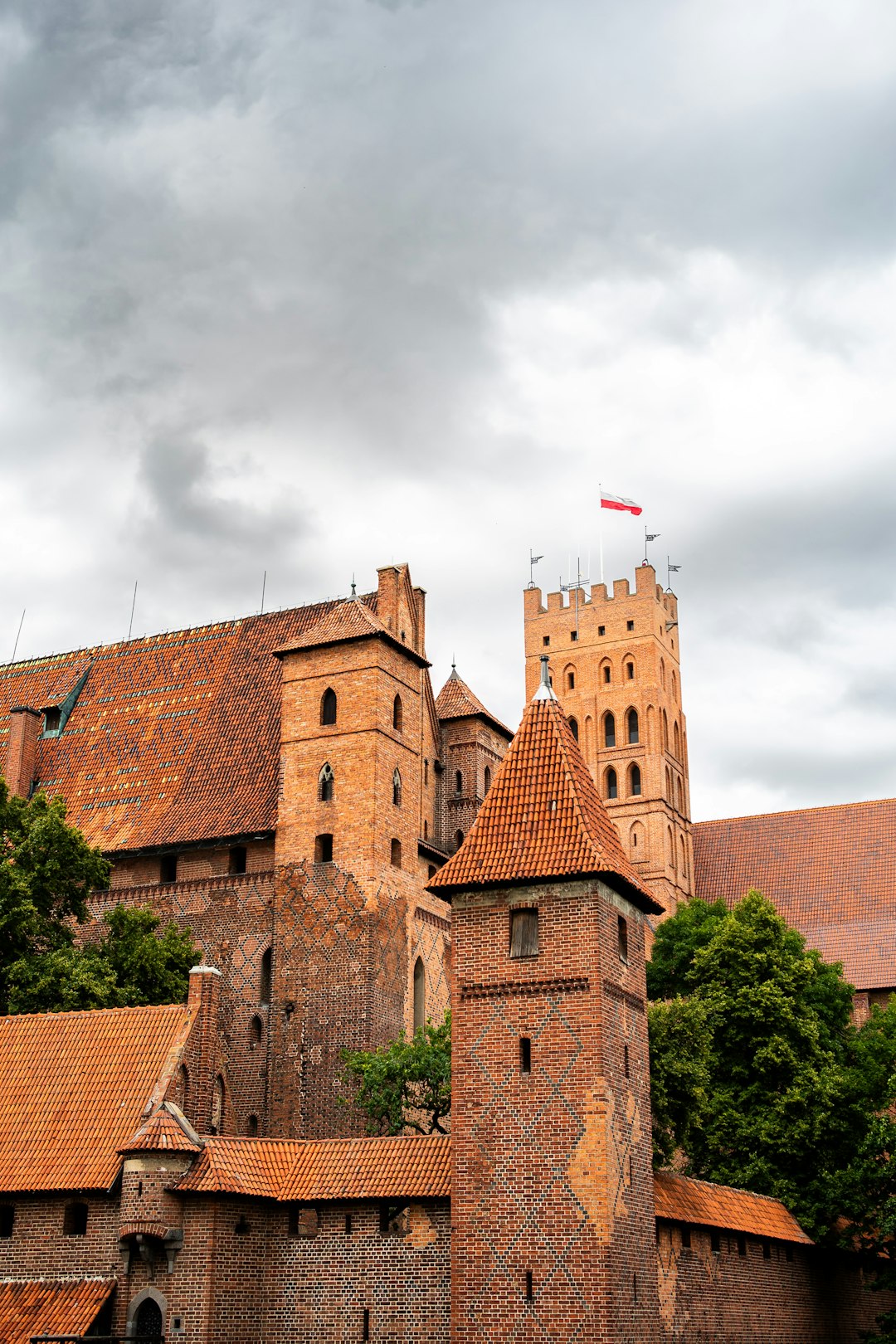 Malbork Castle red-brick fortress reflected in the Nogat River, Poland — largest castle by area in the world